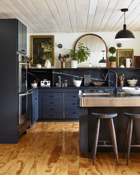 a vintage graphite grey kitchen with flat panel cabinets and a large kitchen island, black soapstone countertops and a backsplash, an open shelf and some artwork