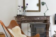 a vintage-inspired space with a faux fireplace, a large mirror in an ornated frame, a hearth, an amber leather butterfly chair