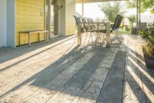 a weathered oak driftwood deck, a modern metal dining table and metal dining chairs, a bench for a cool outdoor space