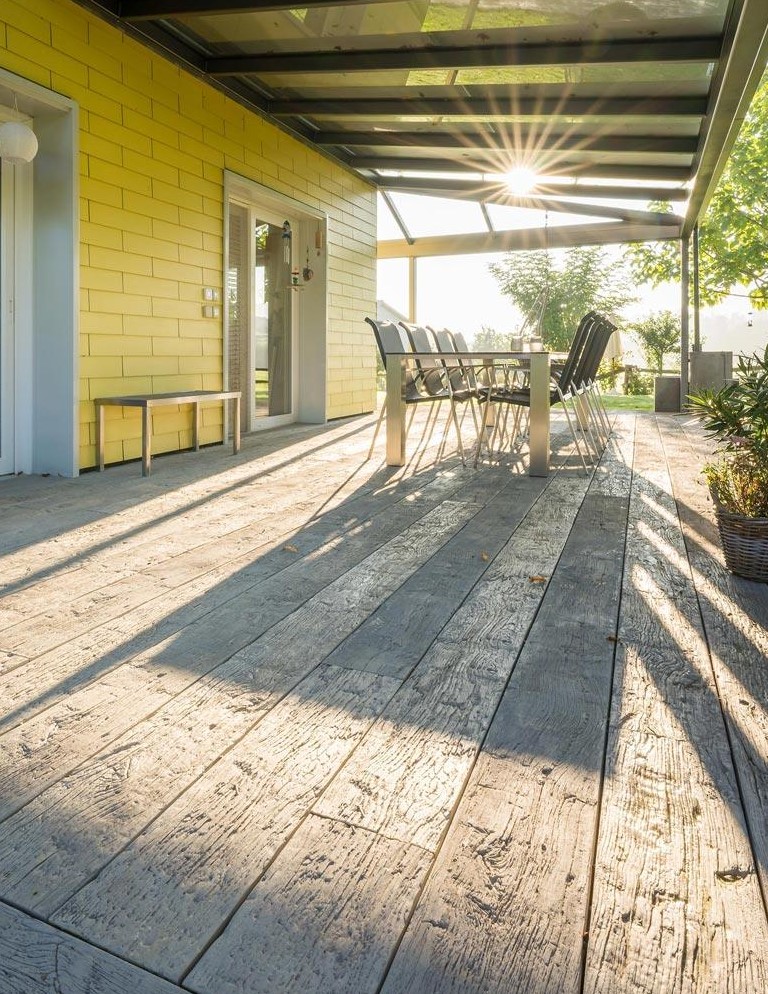 a weathered oak driftwood deck, a modern metal dining table and metal dining chairs, a bench for a cool outdoor space