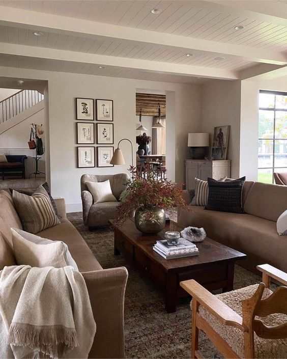 a welcoming modern earthy living room with greige seating furniture, a low dark-stained coffee table, a grid gallery wall and a potted plant