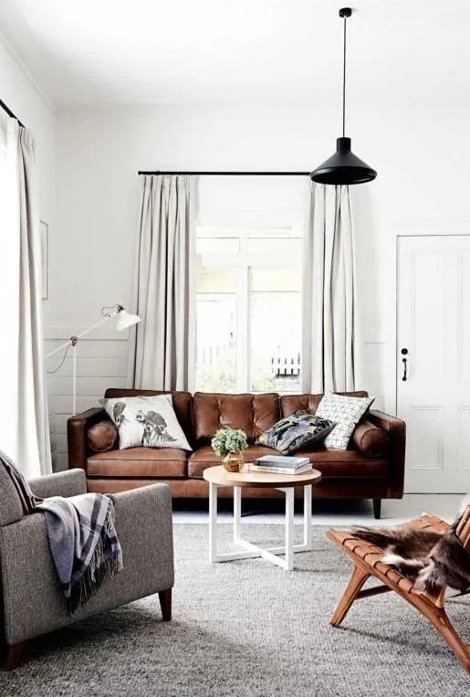 a welcoming neutral living room with a brown leather sofa, a leather stool and a grey chair is cool and stylish