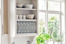 a white farmhouse kitchen with flat panel and open cabinets, a white beadboard backsplash, grey countertops is veyr cozy