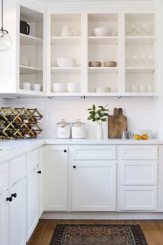 a white farmhouse kitchen with open upper cabinets, a white subway tile backsplash, stone countertops and a wine bottle stand