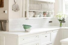 a white farmhouse kitchen with shaker and open cabinets that are used to display dishes and tableware