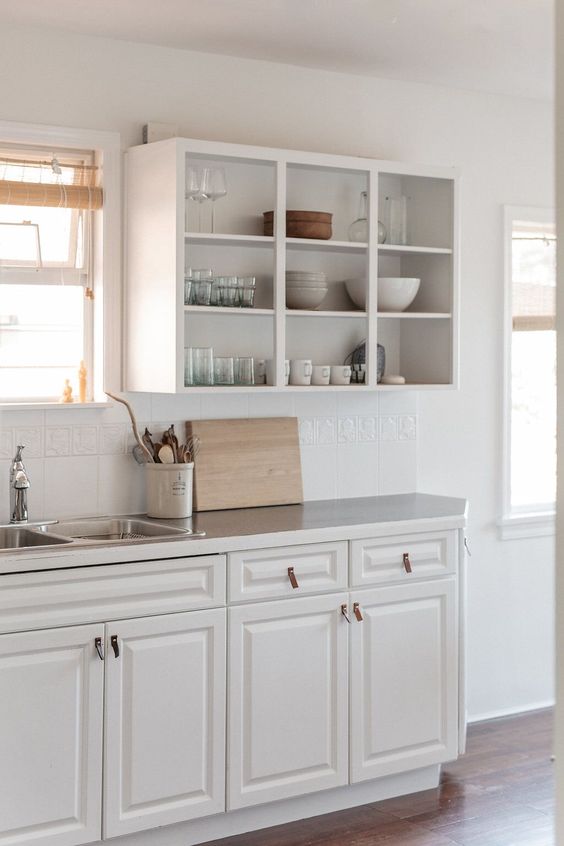 a white kitchen with open upper cabinets, a tile kitchen backsplash and leather pulls is a very cozy idea