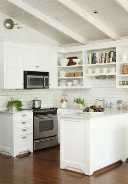 a white kitchen with shaker and open cabinets, a white subway tile backsplash, white countertops and potted greenery