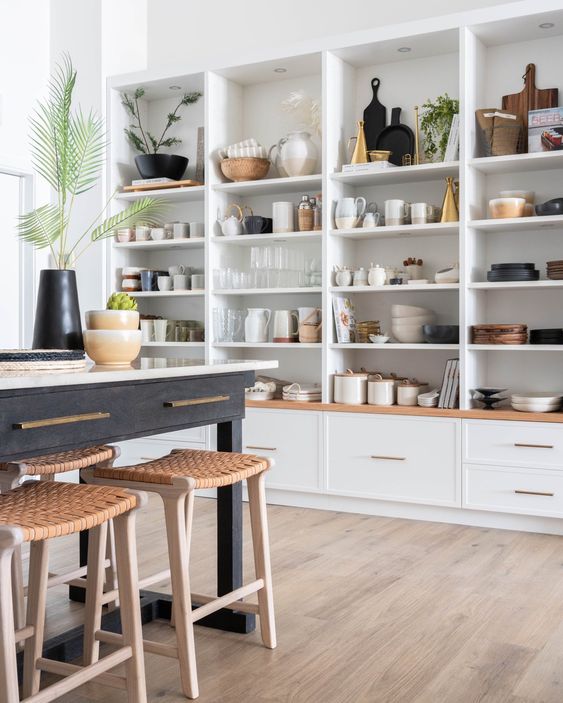 a whole wall taken by open cabinets that are used to display beautiful dishes, vases, cutting boards and other kitchen stuff