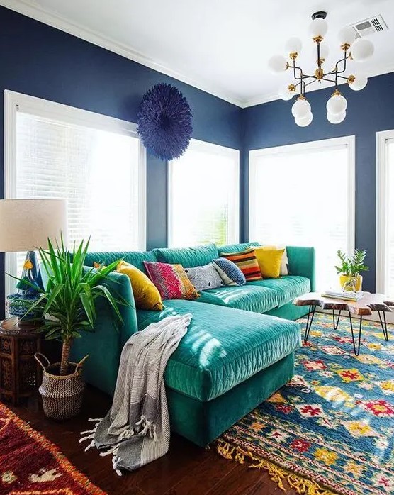 an L-shaped emerald velvet sofa with colorful pillows is the main eye-catcher that adds color to the space