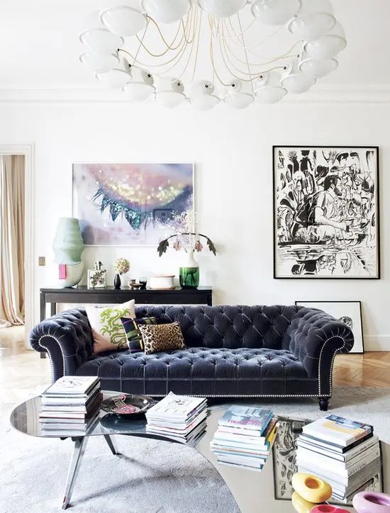 an airy living room in neutral shades with a bold velvet Chesterfield and artworks