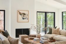 an airy living room with grey sofas, a low coffee table, a creamy chair and striped poufs plus a fireplace