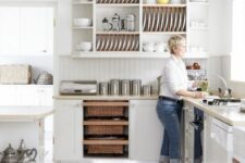 an airy white kitchen with curved cabinets, a kitchen island, an open upper cabinet for displaying dishes and tablware