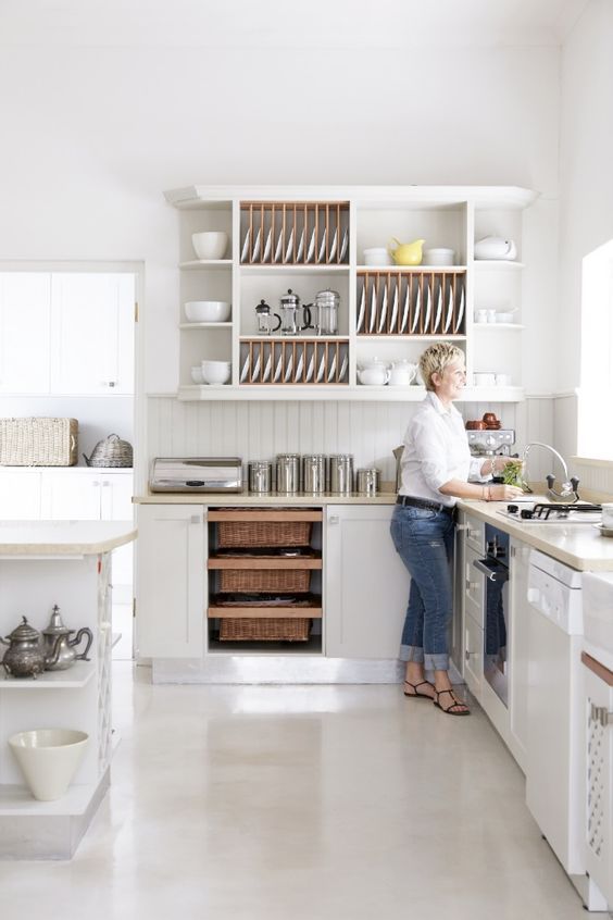 an airy white kitchen with curved cabinets, a kitchen island, an open upper cabinet for displaying dishes and tablware