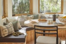 an earthy breakfast nook with a rounded built-in bench, printed pillows, an oval table and a neutral chair