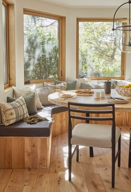 an earthy breakfast nook with a rounded built in bench, printed pillows, an oval table and a neutral chair