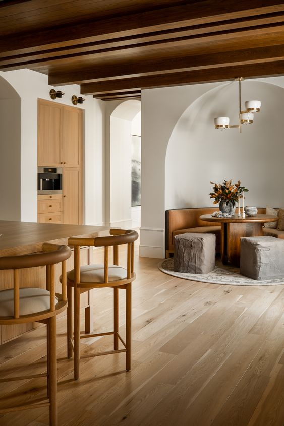 an earthy eclectic space with light and rich stained furniture, poufs that resemble of rocks, a stained wooden ceiling