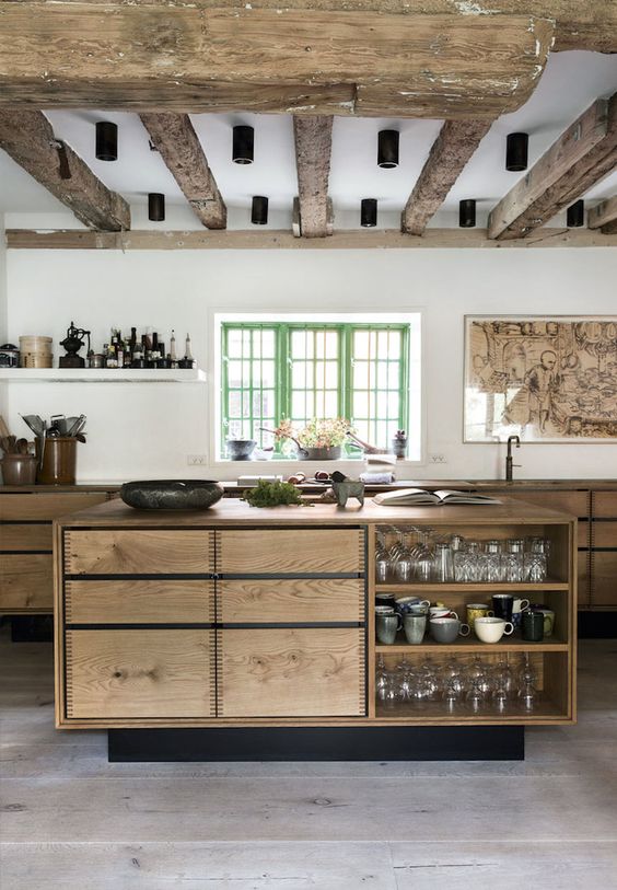 an earthy kitchen with rough wooden beams and stained cabinets, a small storage kitchen island, black fixtures
