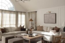 an earthy living room with creamy sofas, a low coffee table, taupe poufs, creamy chairs and printed pillows