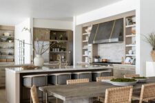 an earthy open layout with light-colored cabinets, a large metal hood, a kitchen island and grey stools and a dining zone