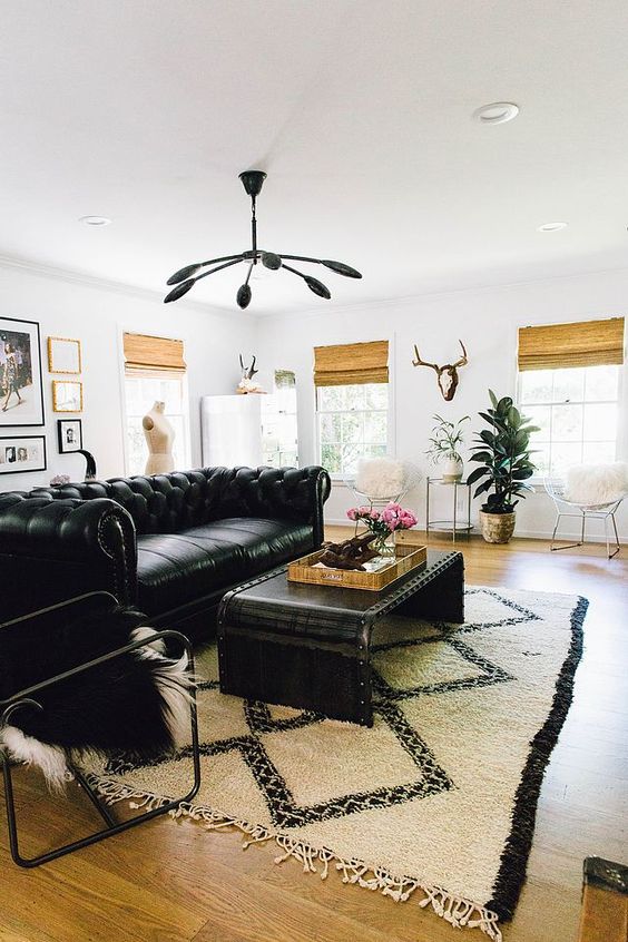 an eclectic living room with a black leather sofa, a black coffee table and chair, a gallery wall, a printed boho rug