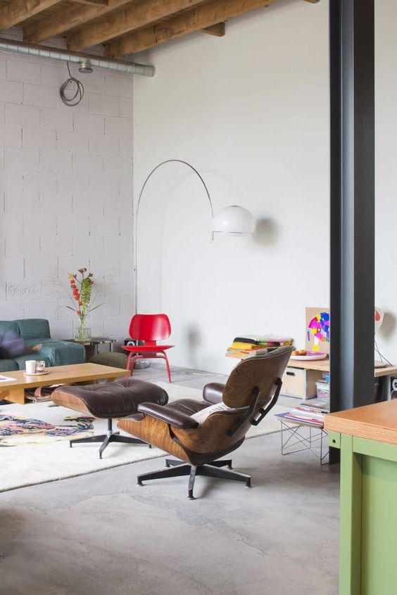 an eclectic living room with a turquoise low sofa, a coffee table, a brown Eames lounger and an ottoman, a red chair and bright artwork