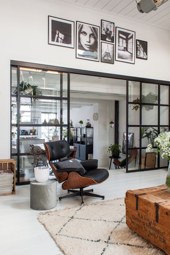 an eclectic space with a black Eames lounger, a metal side table, a crate with magazines, a pallet coffee table