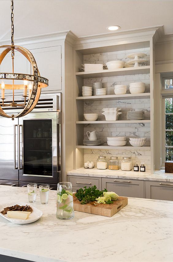 an elegant grey kitchen with shaker and open cabinets, white marble tiles and countertops and a cool sphere pendant lamp