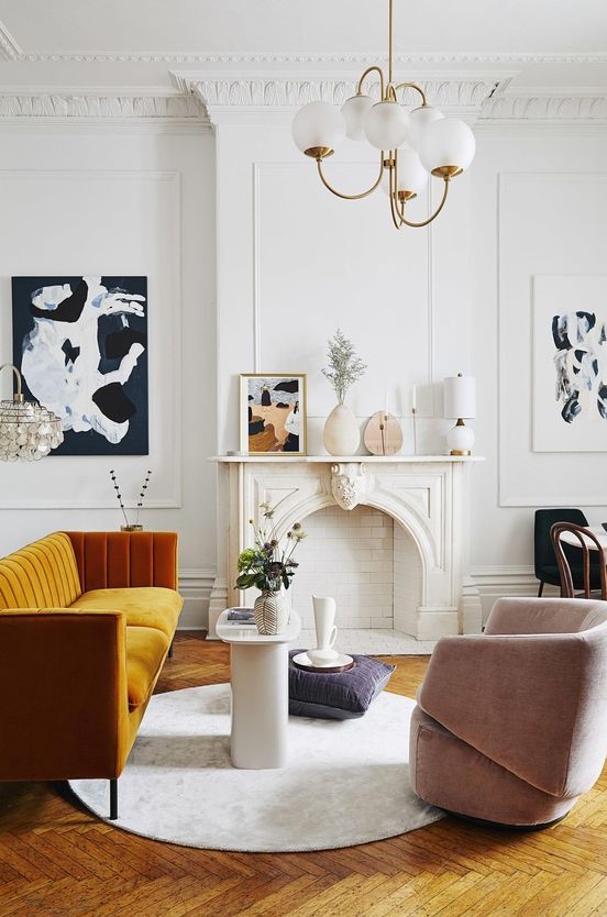 an exquisite Parisian living room with a non-working fireplace, a honey yellow sofa, a blush chair, a retro chandelier and lovely art