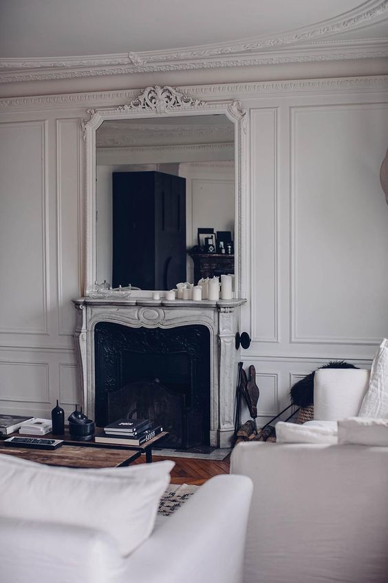 an exquisite living room with an oranted French fireplace, white seating furniture, a coffee table and black decor
