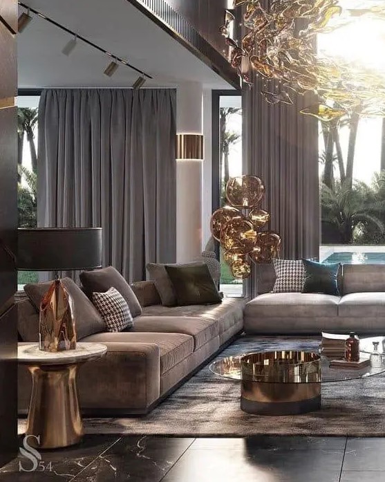 an exquisite taupe living room with brown sofas and curtains, a brown rug, a glass and metal coffee table and a gorgeous chandelier