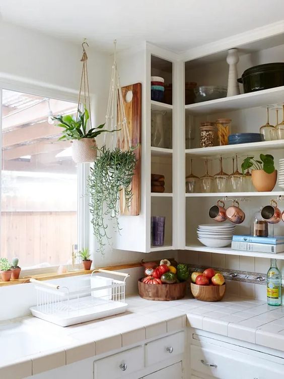 an open upper corner cabinet for displaying dishes, mugs, glasses, potted plants is a cool idea for a kitchen where there's enough storage space