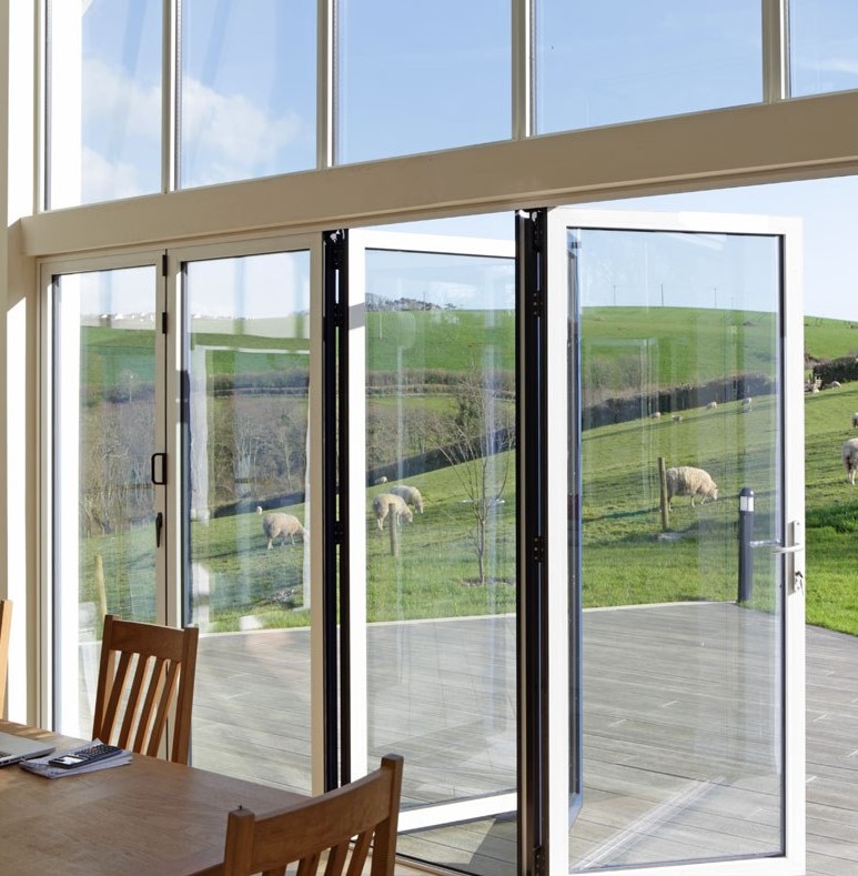 an outdoor-indoor dining space with a glazed wall and a deck clad with smoked oak millboard