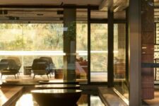 golden oak decking, a pond, black bowls with water create a minimalist and chic space with a sleek and edgy feel