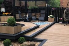golden oak and burnt cedar millboard decking, a jacuzzi, black loungers, a side table and potted and growing plants