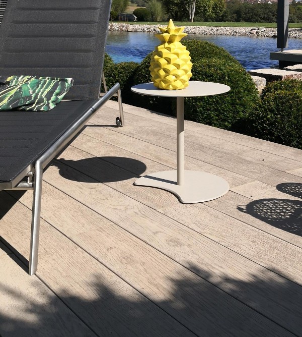smoked oak decking, a black lounger, a neutral side table, a yellow pineapple and a tropical pillow for outdoors