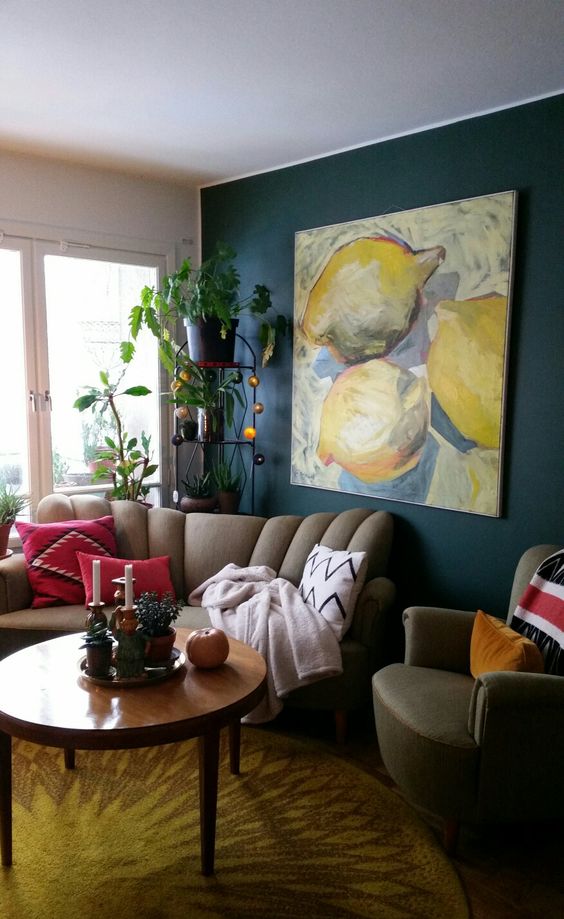 a catchy living room with a navy accent wall, greige seating furniture, an etagere with potted plants and a statement wall art