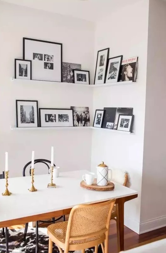 a corner gallery wall with black and white artworks in black frames adds personality to the space and makes it cozier