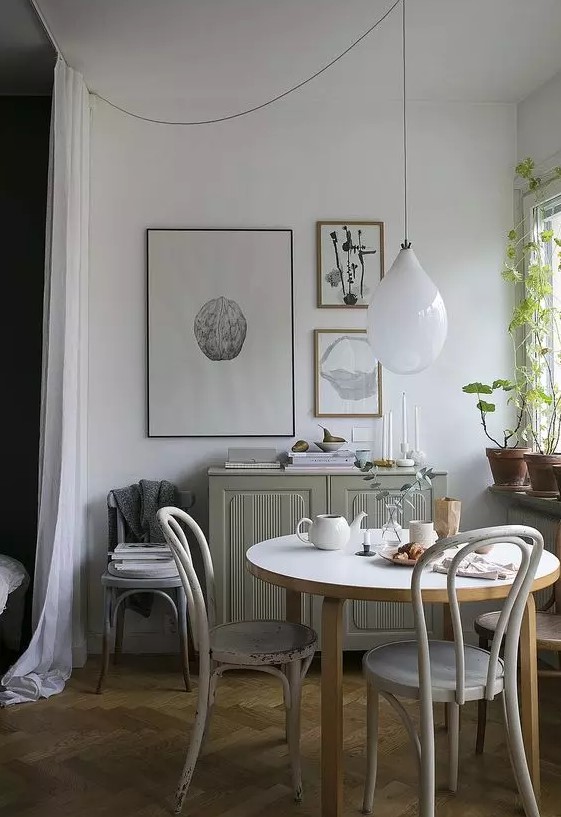 a lovely Scandinavian dining zone with a grey cabinet, a round table and vintage chairs, a mini gallery wall and some greenery