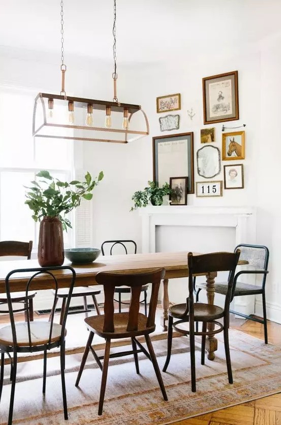 a charming vintage dining room with a vintage table and mismatching chairs, a faux fireplace and a mini gallery wall over it