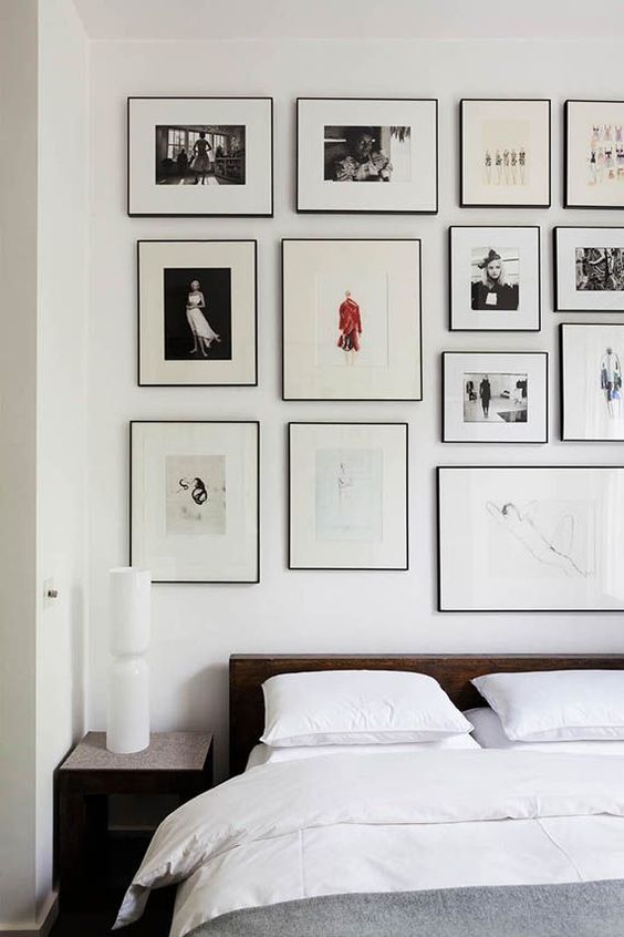 an airy bedroom with a dark-stained bed and nightstands, grey and white bedding, a large gallery wall over the headboard