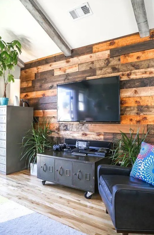 a weathered and stained wood accent wall softens the industrial-inspired living room with vintage touches
