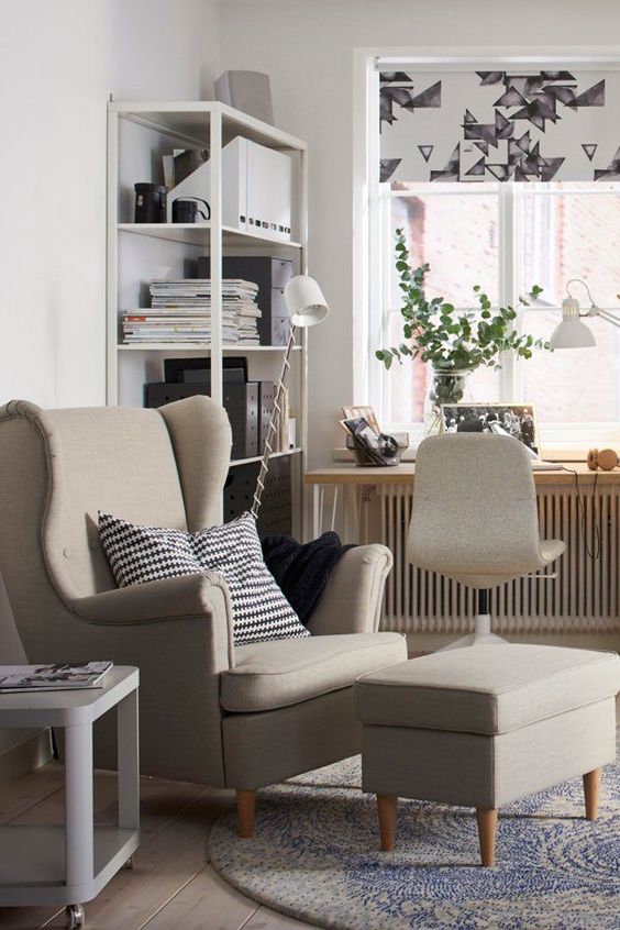 a Nordic space with a shelving unit, a windowsill desk, a neutral chair, a grey Strandmon chair and a footrest, a side table and printed textles