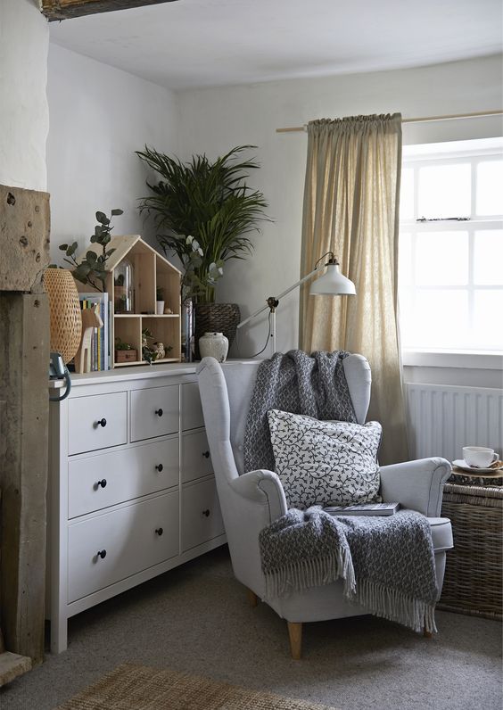 a Scandinavian kids' room with a white IKEA Strandmon chair styled with a pillow and a blanket and a woven chest as a side table