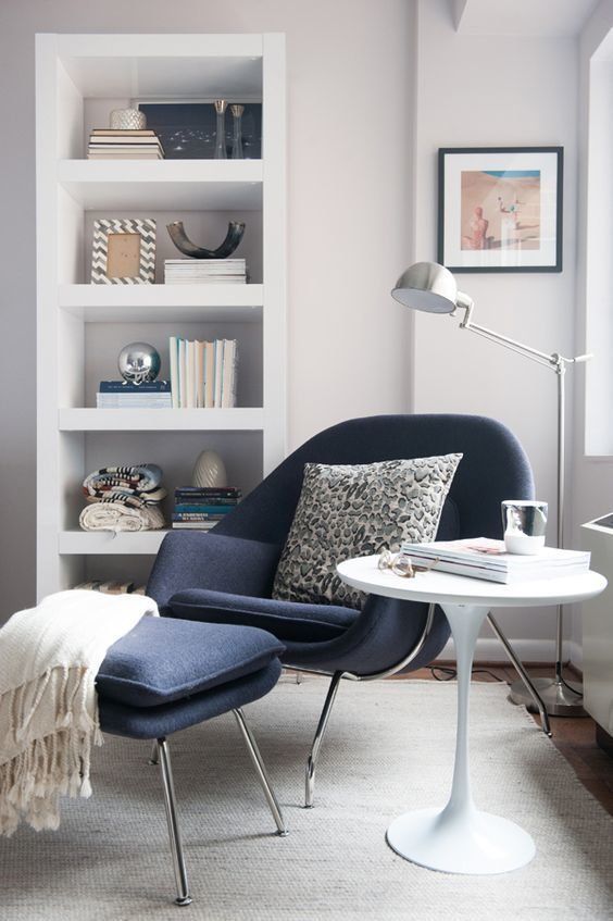 a Scandinavian nook with a white storage unit, a navy Wumb chair and ottoman, a side table and a floor lamp