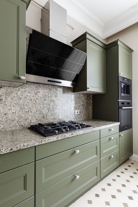 a beautiful olive green kitchen with shaker cabinets, grey stone countertops and a backsplash, black appliances
