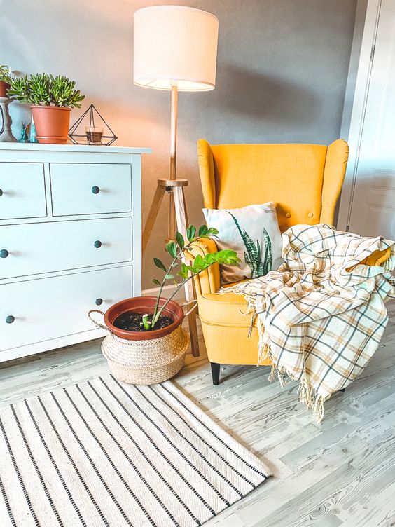 a bold nook with a white Hemnes dresser, a yellow Strandmon chair, printed textiles, a floor lamp and some potted greenery is cool