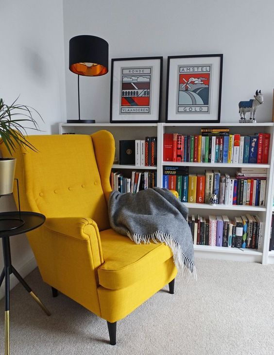 a bold reading nook with bookcases, a yellow Strandmon chair, a cool table lamp, a side table and a grey blanket