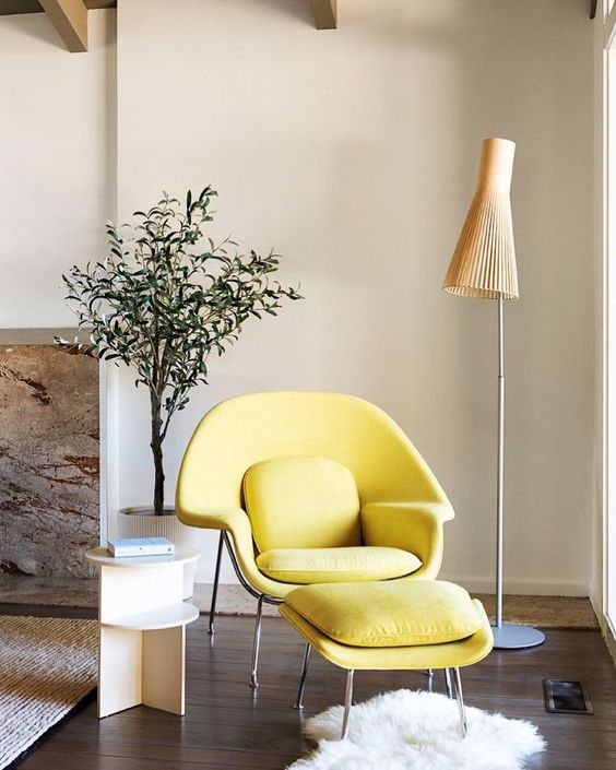 a bright and chic nook with a bold yellow Wumb chair and ottoman, a side table, a floor lamp and a potted plant