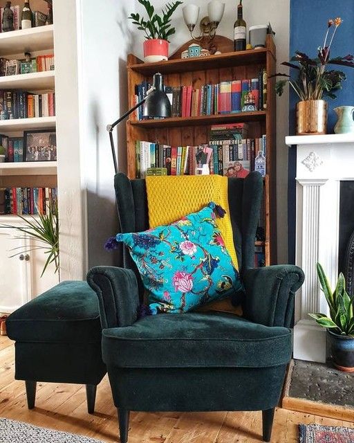 a catchy reading nook by the fireplace, a green Strandmon chair and an ottoman, a stained bookcase and a black lamp