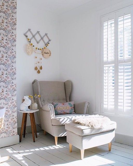 a cozy and light-filled nook by the window with a grey Strandmon chair and an ottoman, printed pillows and some decor on the wall